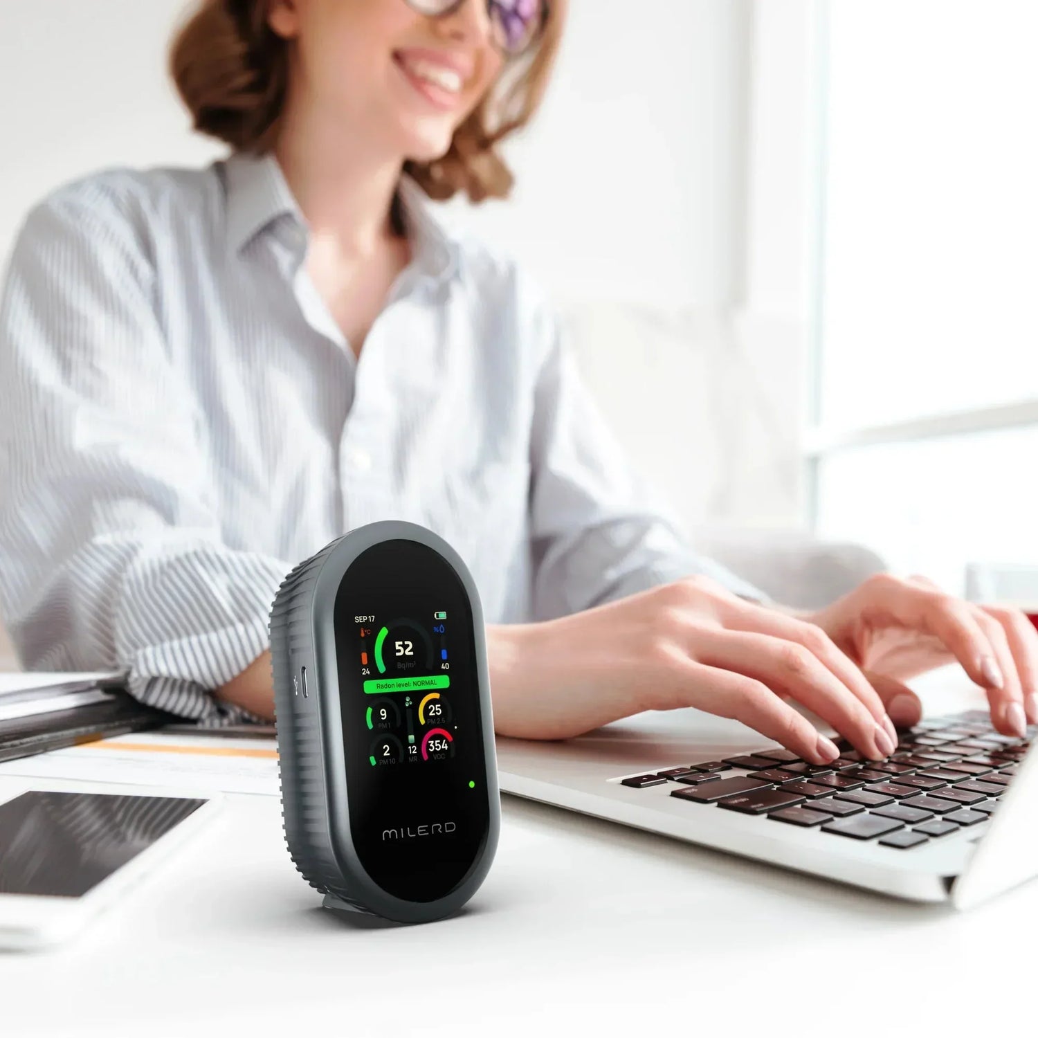 A woman sits at a desk with an air quality analyzers, focused on her work.