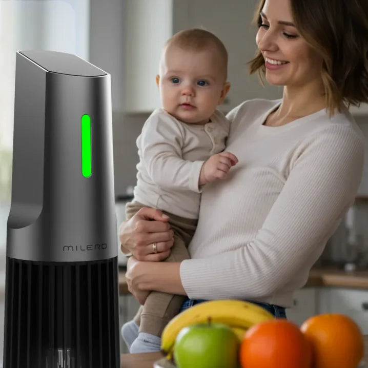 A woman cradles a baby while standing next to a food processor, ready to prepare a meal.